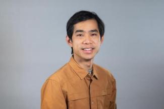 Dr. Edward Lo smiles at the camera in a tan button up. His hair is black and parted to the side. 