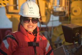 Dr. Shaomin Chen smiles at the camera wearing a white safety helmet and orange suit