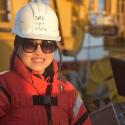 Dr. Shaomin Chen smiles at the camera wearing a white safety helmet and orange suit